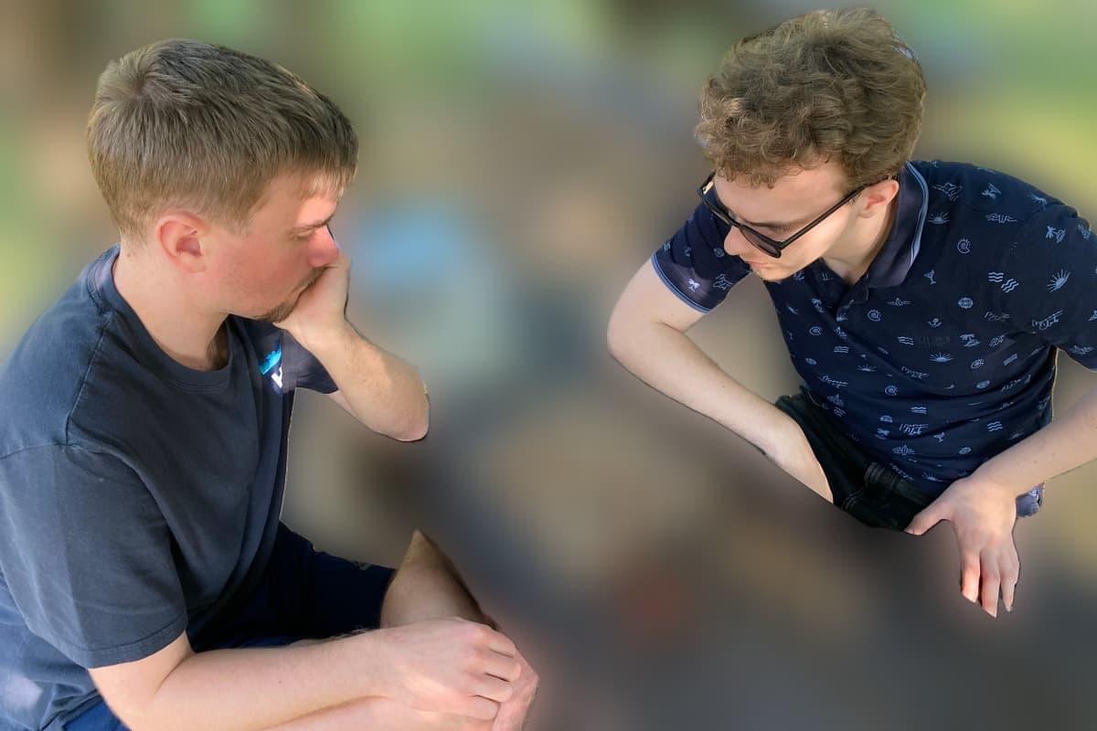 Two people playing chess at a park table stay sharp while the trees and benches behind them are blurred — Blurify result