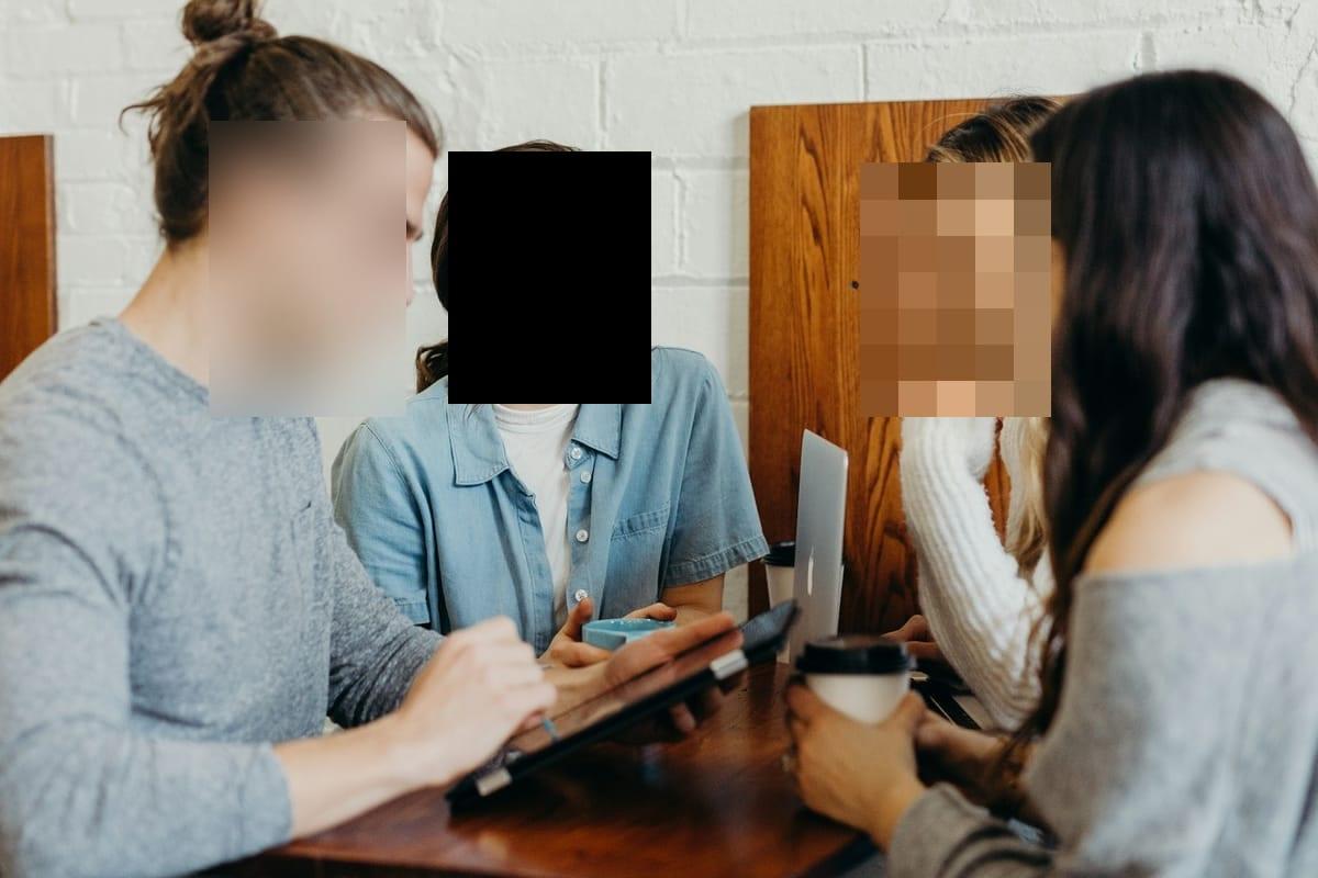 Cafe photo with one face softly blurred, one behind a solid black censor bar, and one pixelated — Blurify result