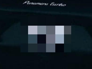 Nahaufnahme vom Heck eines dunklen Autos: An der Stelle des Kennzeichens liegt ein grobes Mosaik aus wenigen großen Farbblöcken, der Schriftzug auf der Heckklappe darüber bleibt scharf